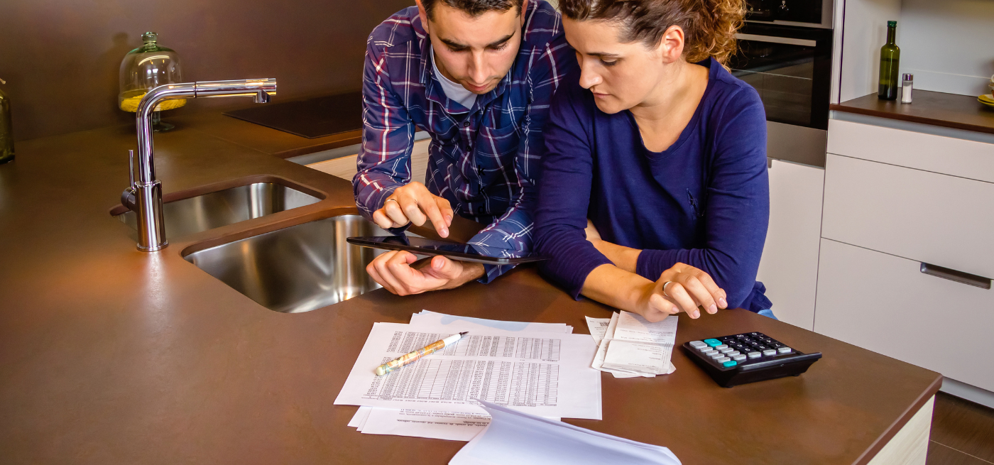 Casal a analisar documentos financeiros e faturas antes de decidir sobre o crédito habitação